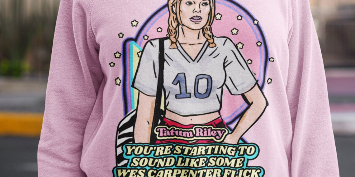Closeup photo of female model wearing pastel pink crew neck sweatshirt with retro illustration of Tatum Riley (Rose McGowan) from Scream (1996) with movie quote below